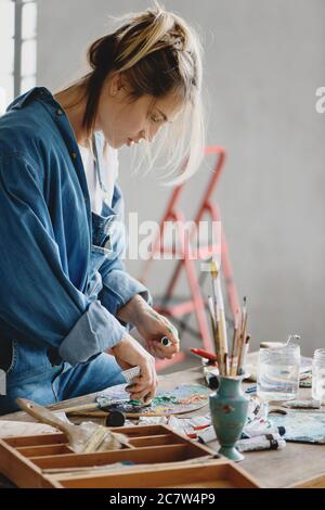 Blonde Frau Mischen Farben auf Palette im Studio. Stockfoto