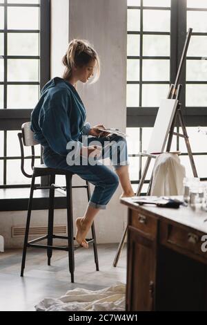 Schöne blonde Künstlerin Malerei Bild im Studio. Stockfoto