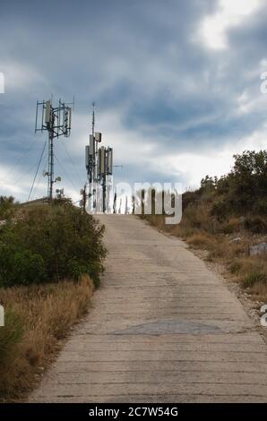 Telekommunikation 4g 5g Türme auf einem Hügel in der Nähe der Stadt Primosten, Kroatien. Kleiner Weg, der zum Hügel führt Stockfoto