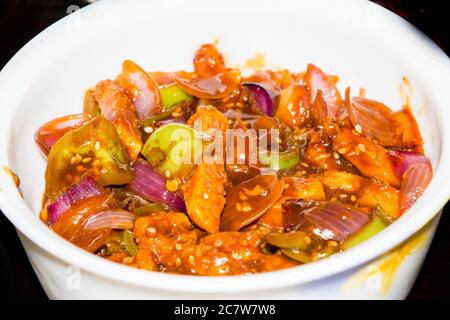 Honigchili-Kartoffeln in würziger Soße, Sesamsamen und grüne Zwiebeln aus der Nähe, horizontale Draufsicht von oben, isoliert auf schwarz Stockfoto