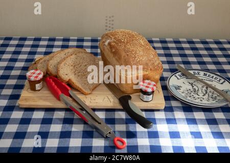 Scheiben frisch gebackenes Brot mit Sesamsamen auf einem hölzernen Brotbrett Stockfoto