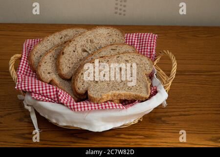 Scheiben frisch gebackenes braunes Brot mit Sesamsamen in einem Weidenkorb Stockfoto