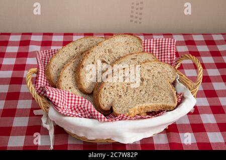 Scheiben frisch gebackenes braunes Brot mit Sesamsamen in einem Weidenkorb Stockfoto