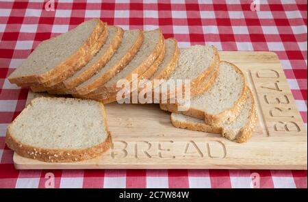 Scheiben frisch gebackenes Weißbrot mit Sesamsamen auf einem hölzernen Brotbrett Stockfoto