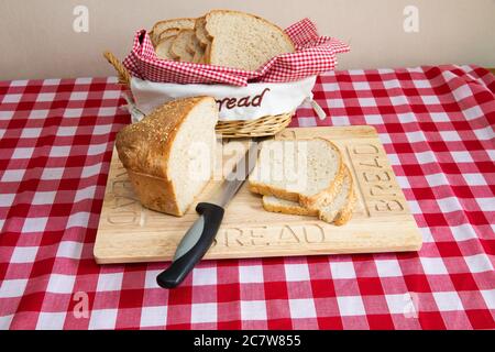 Scheiben frisch gebackenes Weißbrot mit Sesamsamen auf einem hölzernen Brotbrett Stockfoto