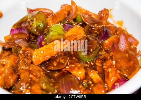 Honig-Chilipartoffeln in einer würzigen Sauce, Sesam und grüne Zwiebeln in der Nähe, beliebte indisch-chinesische Küche. Selektiver Fokus Stockfoto