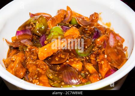 Honig-Chilipartoffeln in einer würzigen Sauce, Sesam und grüne Zwiebeln in der Nähe, beliebte indisch-chinesische Küche. Selektiver Fokus Stockfoto