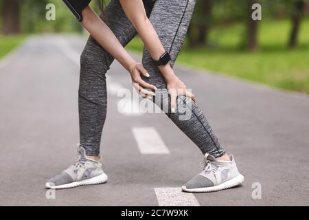 Wadenverletzung. Sportliche Frau massiert Bein, mit Muskelschmerzen nach dem Joggen im Freien Stockfoto