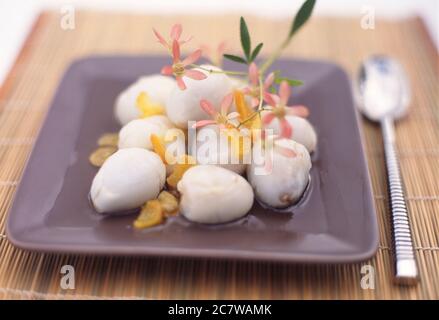 Litschi und Ingwerstücke in Sirup auf einem Teller Stockfoto