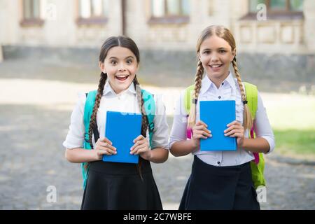 Große Überraschung für sie. Schülerinnen lernen Thema zusammen. Viel Spaß beim Lernen. Glückliche Mädchen in Schuluniform. Überrascht Teenager-Studenten mit Rucksack halten Copybook. Bildung in der Grundschule. Stockfoto