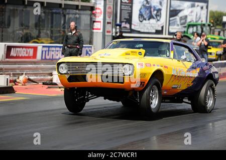 Ein Chevrolet Camaro steht auf seinen Hinterrädern und beschleunigt von der Startlinie am Santa Pod Raceway Drag Strip weg Stockfoto