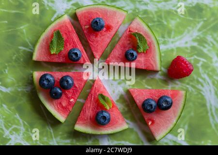 Scheiben Wassermelone mit roten Früchten und Minze bedeckt. Stockfoto