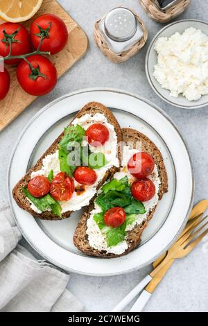 Bruschetta mit Ricotta-Käse, gebratene Tomaten, Basilikum und Olivenöl. Draufsicht Stockfoto