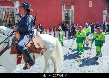 Mexikanische berittene Polizei reiten ihre Pferde in einer Parade zum 251. Geburtstag des mexikanischen Unabhängigkeitshelden Ignacio Allende als Aufräumen Crew folgt hinter 21. Januar 2020 in San Miguel de Allende, Guanajuato, Mexiko. Allende, aus einer wohlhabenden Familie in San Miguel, spielte eine wichtige Rolle im Unabhängigkeitskrieg gegen Spanien 1810 und später von seiner Heimatstadt geehrt durch seinen Namen. Stockfoto