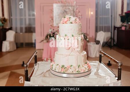 Dreistufige Hochzeitstorte mit cremigen Rosen dekoriert Stockfoto