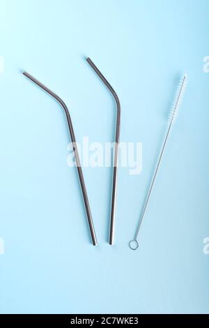 Trinkhalme aus Edelstahl mit kleiner Bürste auf hellblauem Hintergrund Stockfoto