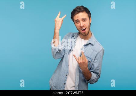 Ja, das ist verrückt! Portrait von begeisterten Mann in Arbeiter Denim-Shirt zeigt Rock and Roll Hand Geste und schreien vor Freude, macht Teufelshörner Stockfoto