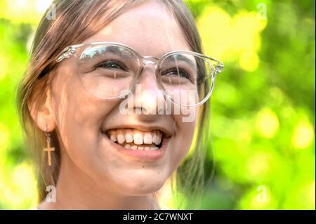 Helles Porträt eines lachenden Teenagers in einer Brille. Fröhliches Mädchen Stockfoto