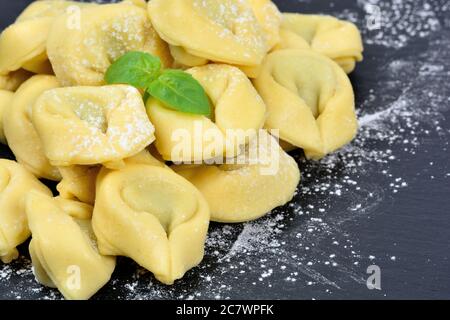 Frische Tortellini auf einem Schiefer mit Mehl Stockfoto