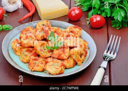Nahaufnahme der traditionellen italienischen Tortellini Pasta auf einem Teller auf einem braunen Holztisch Stockfoto