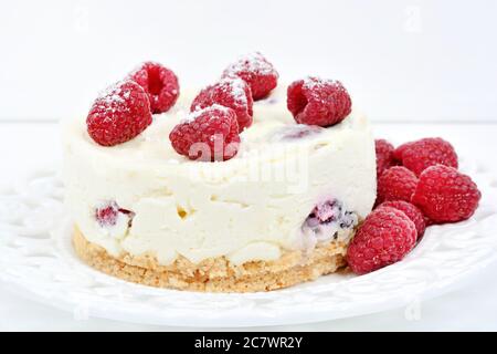 Nahaufnahme von Mini-Käsekuchen mit weißer Schokolade und Himbeeren auf weißem Holzhintergrund Stockfoto