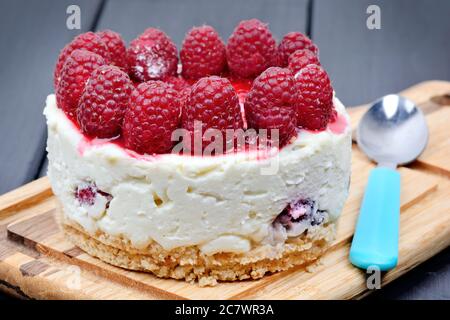 Nahaufnahme von Mini-Käsekuchen mit weißer Schokolade und Himbeeren auf Schneidebrett Stockfoto