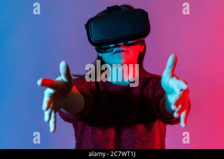 Nahaufnahme Mädchen mit Virtual-Reality-Brille auf dem Kopf spielen Spiel Simulator, stehend ausgestreckte Hände, halten Objekt im Cyberspace, mit VR-Headset Stockfoto
