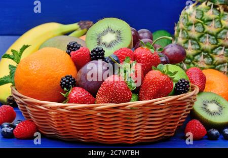 Frisches Obst in einem Korb auf blauem Holztisch Stockfoto