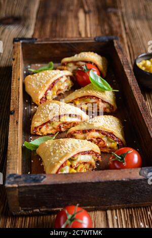 Köstliche Blätterteig Pizza Dreiecksbrötchen gefüllt mit Tomatensauce, Schinken, Käse, Mais, Oliven und bestreut mit Sesam Stockfoto