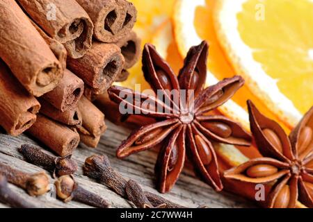 Zimtstangen mit Sternanis, Nelken und Orangenfrucht auf altem Holztisch Stockfoto