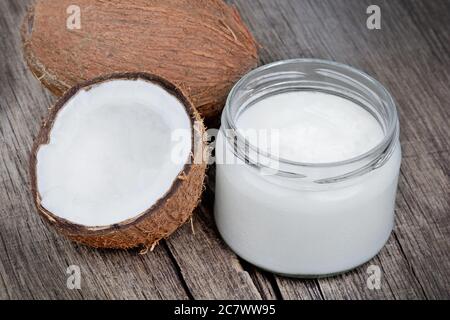 Kokosöl und frische Kokosnüsse auf altem Holztisch Stockfoto