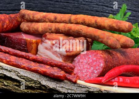 Verschiedene Sorten von Würsten mit Chili und Petersilie auf Schneidebrett Stockfoto