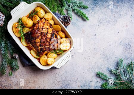 Weihnachten gebackene Schweinelende mit Kartoffeln in der Backplatte, dunkel festlichen Hintergrund. Weihnachtsfleisch Konzept. Stockfoto