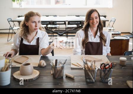 Weibliche Töpfer machen Tonkeramik am Tisch mit einem anderen Holzwerkzeug Stockfoto