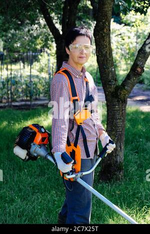 Porträt einer Gärtnerin mit Grasschneider im Hinterhof. Gartenarbeit Konzept. Stockfoto