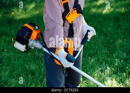 Weibliche Hände halten Benzin-Saiten-Trimmer, Nahaufnahme. Gartenarbeit Konzept. Stockfoto