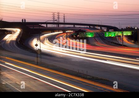 Verschwommene Scheinwerfer und Rücklichter vorbeifahrenden Autos an der Kreuzung der Interstate 5 und 210 im San Fernando Valley bei Sonnenaufgang Stockfoto