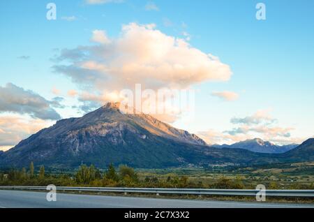 Schöne hohe Berge mit Grüns bedeckt und unter dem schimmernden wolkiger Himmel Stockfoto