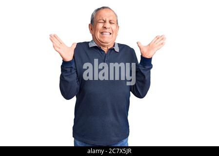 Senior stattlichen Mann trägt Casual Polo feiert verrückt und verrückt für den Erfolg mit den Armen angehoben und geschlossenen Augen schreien aufgeregt. Sieger Konzept Stockfoto