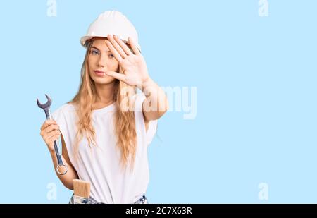 Schöne kaukasische Frau mit blonden Haaren trägt Hardhut und Bauherrenkleidung mit offener Hand tun Stop-Zeichen mit ernst und zuversichtlich Ausdruck, d Stockfoto