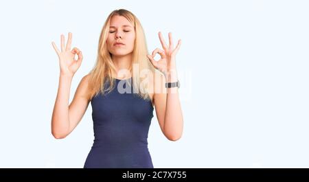 Junge schöne blonde Frau trägt Freizeitkleid entspannen und lächeln mit geschlossenen Augen tun Meditation Geste mit Fingern. Yoga-Konzept. Stockfoto
