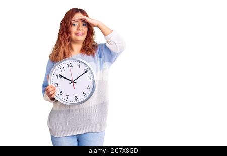 Junge latinerin mit großer Uhr gestresst und frustriert mit Hand auf Kopf, überrascht und wütend Gesicht Stockfoto