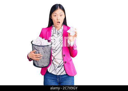 Junge schöne chinesische Frau hält Papierbehälter voll von zerknitterte Papiere verängstigt und erstaunt mit offenem Mund für Überraschung, Unglauben Gesicht Stockfoto
