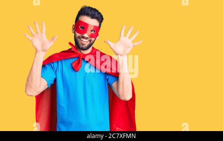 Junger schöner Mann mit Bart trägt Superhelden Kostüm zeigt und zeigt mit den Fingern Zahl zehn, während lächelnd zuversichtlich und glücklich. Stockfoto