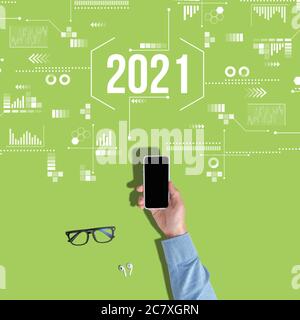 Hände mit Smartphone mit Draufsicht auf grünem Hintergrund mit Jahr 2021. Stockfoto