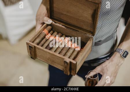 Nahaufnahme eines jungen Mannes, der eine Holzkiste mit Kubaner hält Zigarren Stockfoto