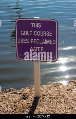 Ein Schild am Golfplatz warnt davor, dass Wasser nicht zum Trinken in der Nähe des Teiches zurückgewonnen wird, mit einem Sonnenauflauf an einem hellen Morgen Stockfoto