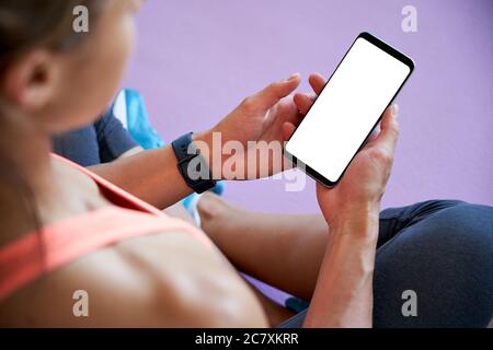 Fit sportliche Frau hält Telefon Modell bis weißen Bildschirm mit Fitness Yoga App. Stockfoto