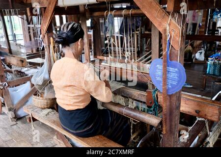 Eine burmesische Frau, die am Holzwebstuhl sitzt. Mit Faser der Lotuswurzel mit Baumwolle und Seide zu Schal und longyi zu machen. Traditionelle Industrie in Inle See Stockfoto