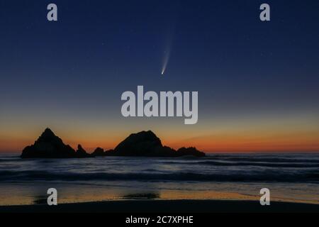 Komet Neowise nach Sonnenuntergang über Seal Rock, San Francisco, Kalifornien, USA als die Wellen am reflektierenden Strand zusammenbrechen. Stockfoto